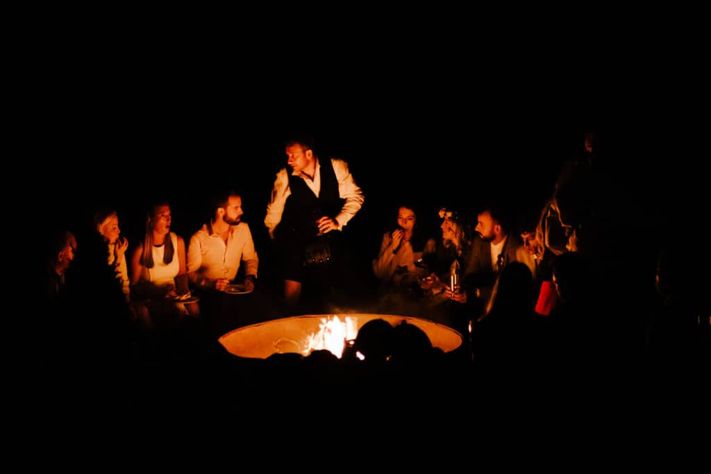 Wedding guests sharing a good time around an evening firepit