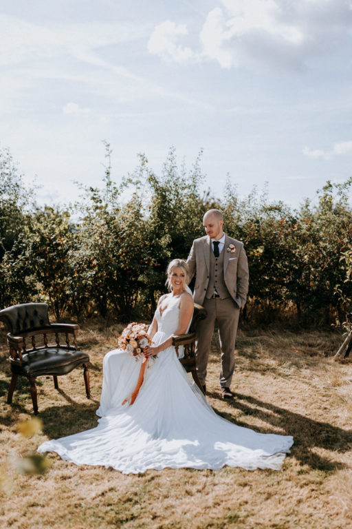 A bride and groom posing in the secret orchard of The Ferry House wedding venue in Kent.