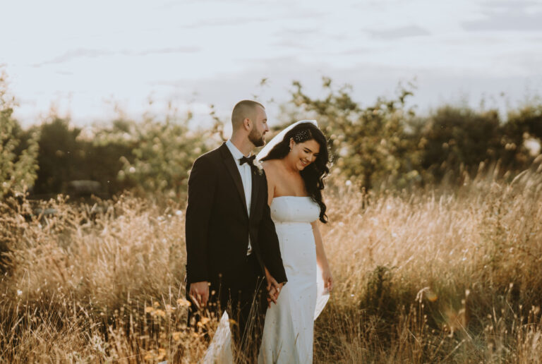 A couple walking through meadow grasses at The Ferry House wedding venue in Kent