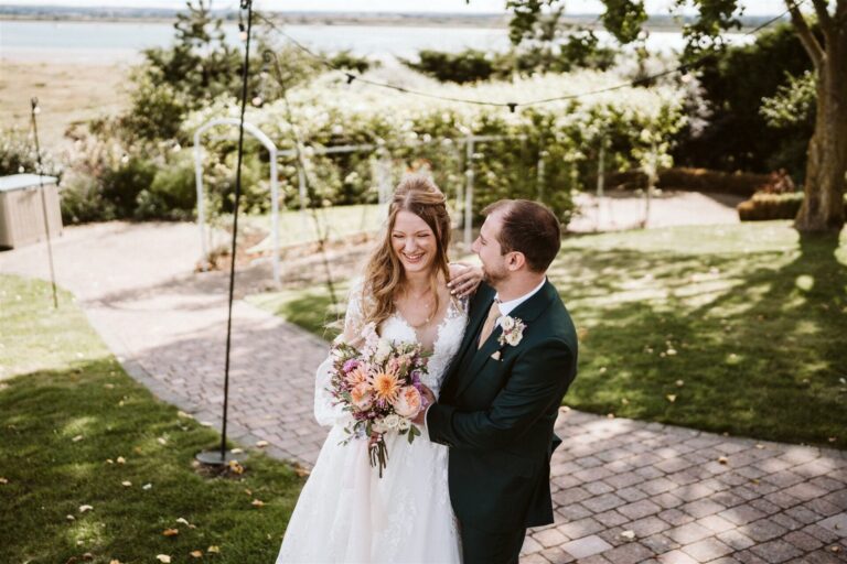 A wedding couple laughing in the garden of The Ferry House barn wedding venue in Kent