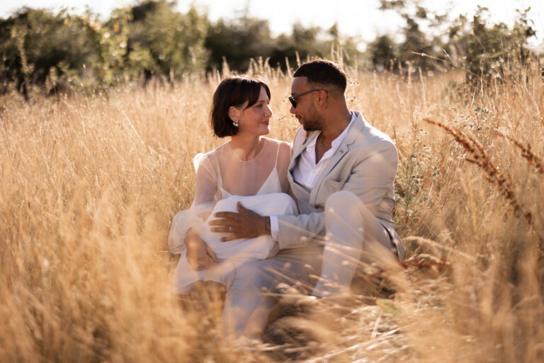 A cool wedding couple sat among gold wild grasses at twilight