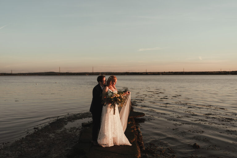 Two brides in front of the Swale estuary in Kent at sunset.