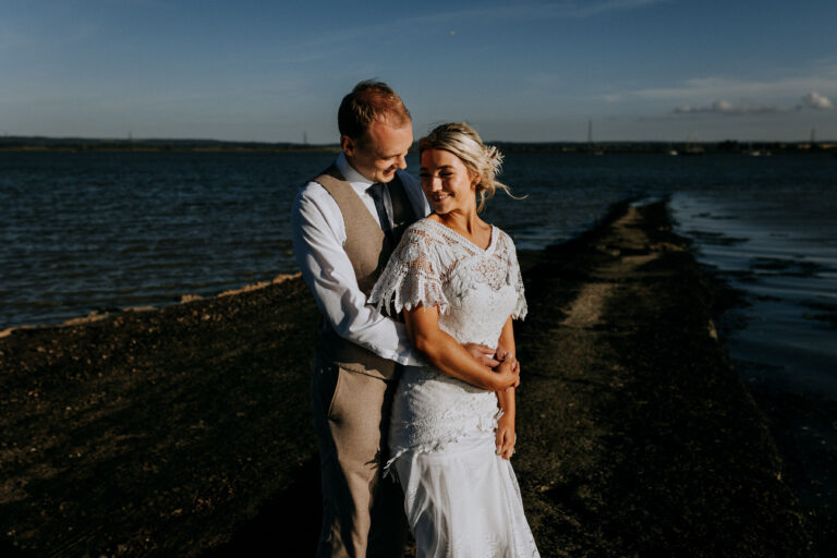 A wedding couple sharing a romantic moment in front of the Swale estuary in Kent