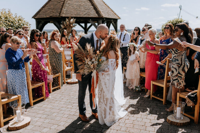 Newlyweds walking down the aisle after their outdoor ceremony at The Ferry House in Kent.