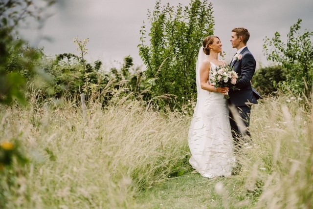 A bride and groom in the secret orchard at Kent barn wedding venue, The Ferry House.