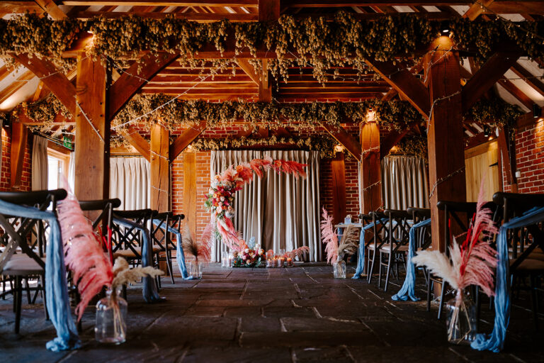 A vibrant wedding crescent moon gate, with colourful flowers and pink feathers