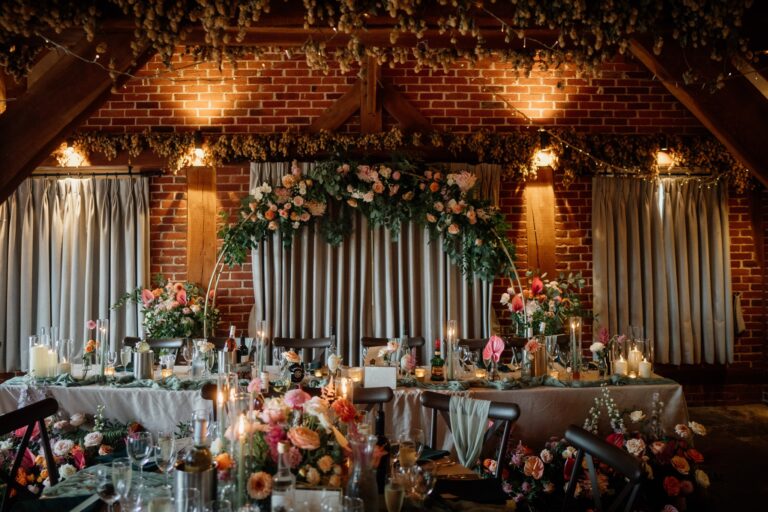 A stunning colourful wedding flower arch behind the top table