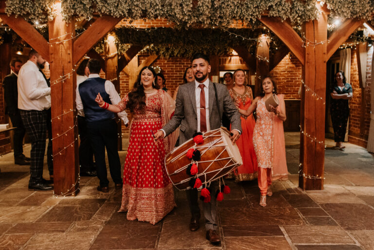 Bride in traditional Indian wedding attire, making a drummed entrance to her wedding reception