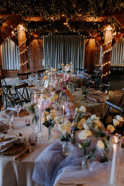 Caterpillar tables with wedding decor at The Ferry House barn wedding venue in Kent